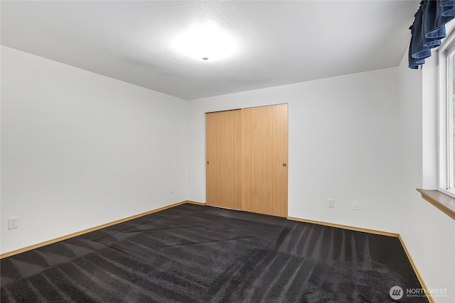 unfurnished bedroom with baseboards and dark carpet