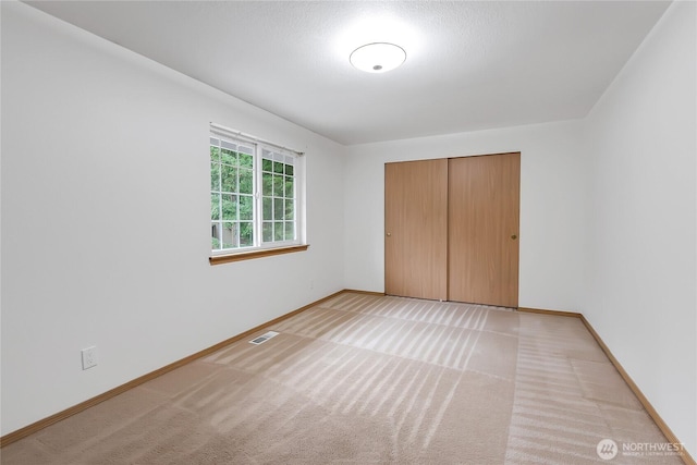 unfurnished bedroom featuring visible vents, light colored carpet, and baseboards