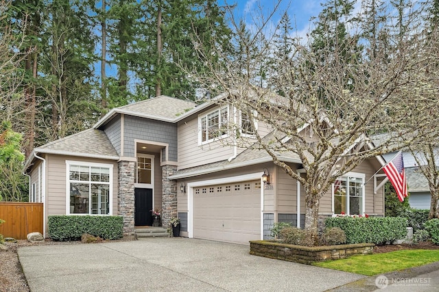 view of front of house with a shingled roof, fence, concrete driveway, stone siding, and an attached garage