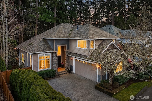 view of front facade with stone siding, driveway, and a shingled roof