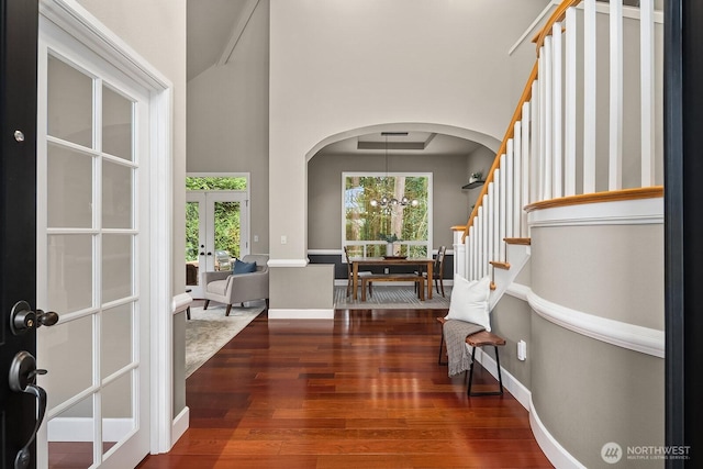 entrance foyer with stairway, baseboards, arched walkways, french doors, and wood-type flooring