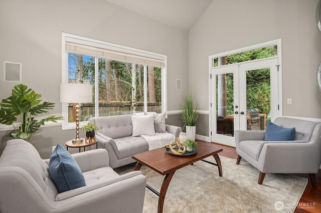 living room with french doors, baseboards, high vaulted ceiling, and wood finished floors