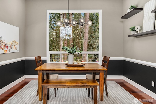 dining area with baseboards, an inviting chandelier, and wood finished floors