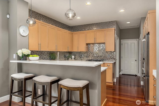 kitchen with a kitchen bar, dark wood-type flooring, light brown cabinetry, and freestanding refrigerator