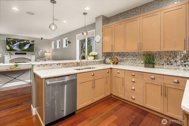 kitchen with stainless steel dishwasher, a peninsula, light countertops, and a sink