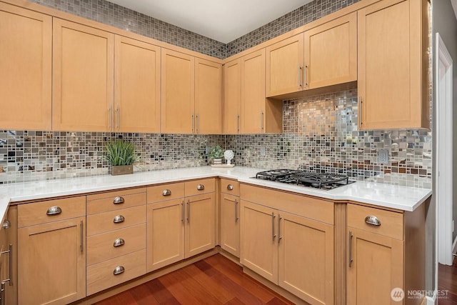 kitchen with tasteful backsplash, light brown cabinets, light countertops, stainless steel gas stovetop, and dark wood-style floors