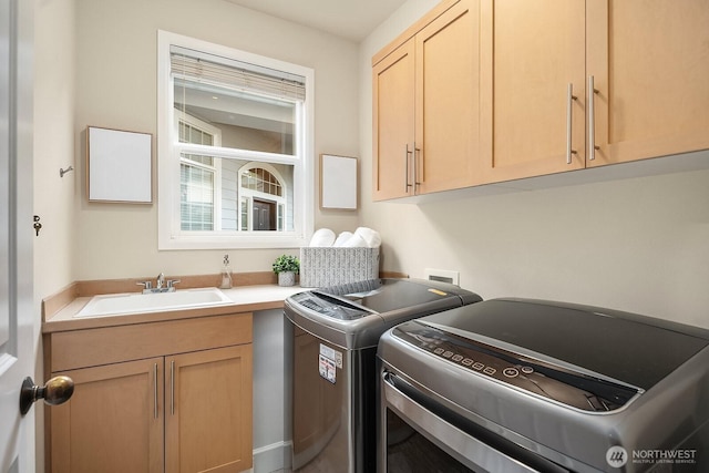 clothes washing area with a sink, cabinet space, and separate washer and dryer