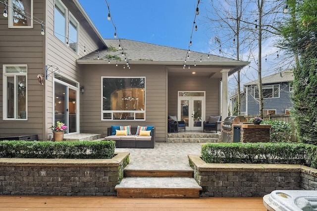 rear view of property with an outdoor living space, french doors, roof with shingles, an outdoor kitchen, and a patio area