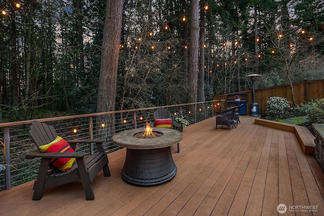 wooden terrace featuring a fire pit and fence