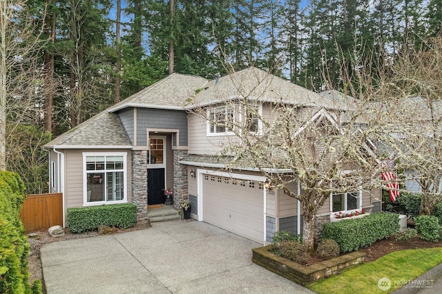 view of front facade with a shingled roof, fence, concrete driveway, stone siding, and an attached garage