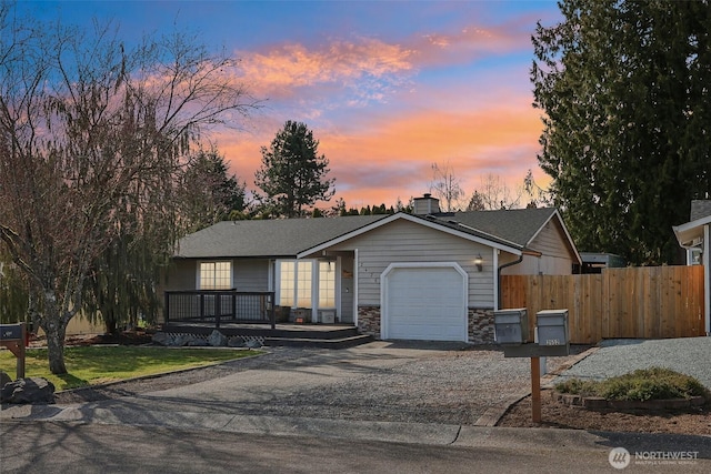 view of front of property with fence, an attached garage, a chimney, stone siding, and aphalt driveway