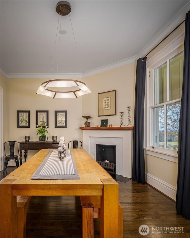 dining area with baseboards, wood finished floors, ornamental molding, and a fireplace