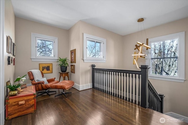 sitting room with wood finished floors, an upstairs landing, baseboards, and a healthy amount of sunlight