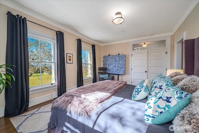 bedroom with multiple windows, wood finished floors, and ornamental molding