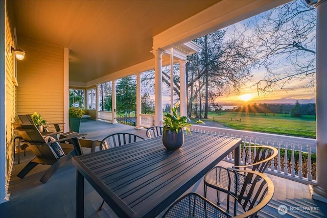 patio terrace at dusk featuring outdoor dining area and a porch