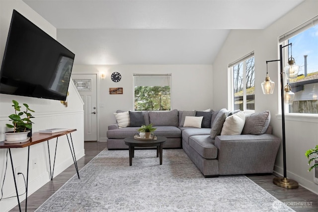 living room featuring wood finished floors, baseboards, and vaulted ceiling