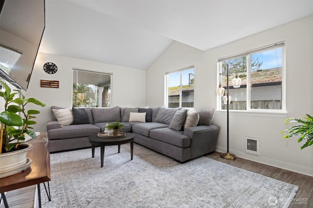 living room featuring visible vents, lofted ceiling, baseboards, and wood finished floors