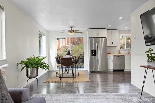 kitchen with dark wood finished floors, appliances with stainless steel finishes, white cabinets, light countertops, and baseboards