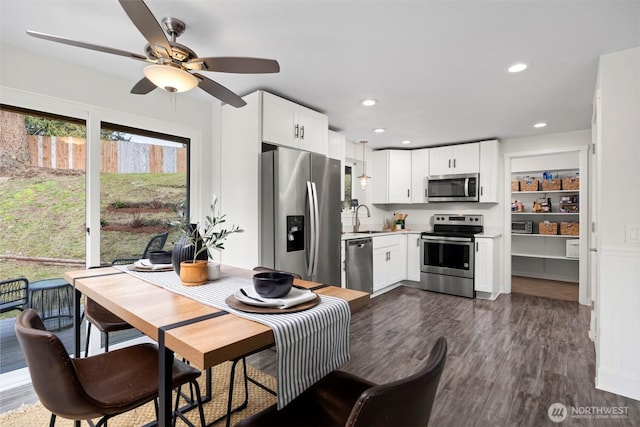 kitchen with a sink, dark wood-style floors, white cabinetry, appliances with stainless steel finishes, and light countertops