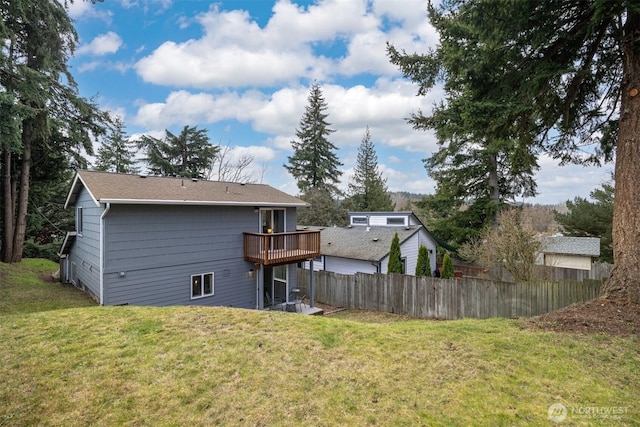 rear view of house with a yard, a deck, and fence