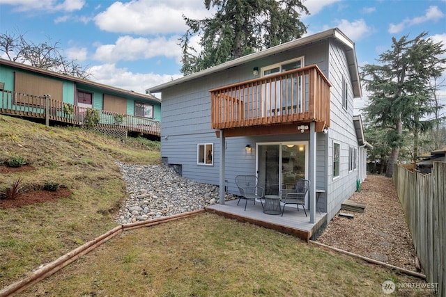 back of house with a balcony, a yard, and fence