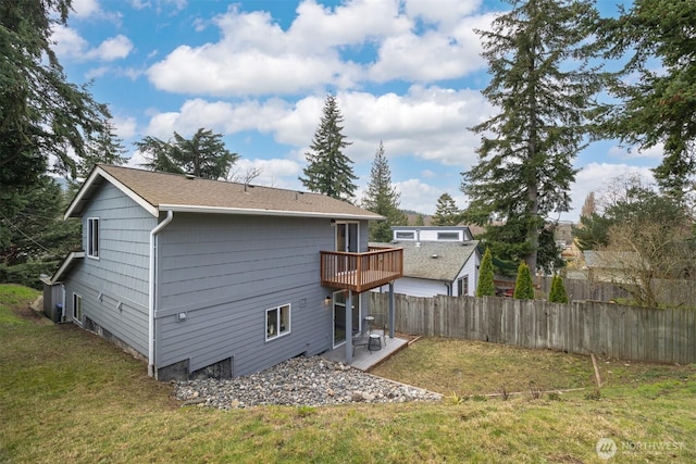 back of property with a lawn, a wooden deck, and fence