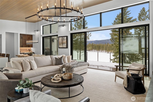 living room featuring a wealth of natural light, a notable chandelier, wooden ceiling, and a towering ceiling