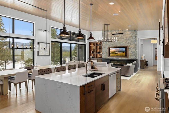 kitchen featuring a sink, a stone fireplace, wooden ceiling, and appliances with stainless steel finishes