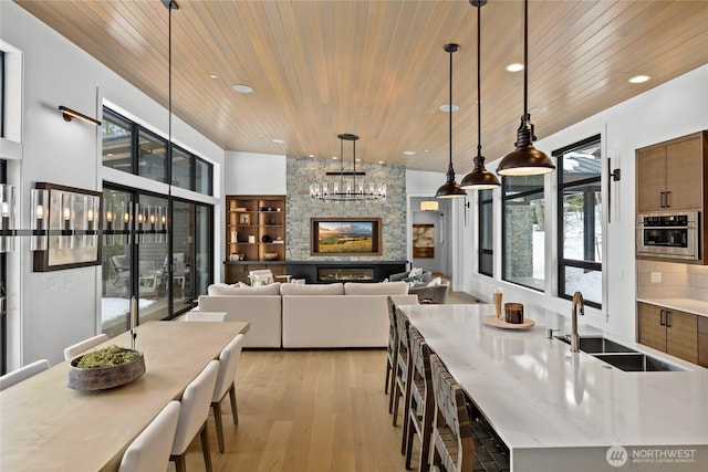 kitchen with oven, a sink, wood ceiling, decorative light fixtures, and light wood-type flooring