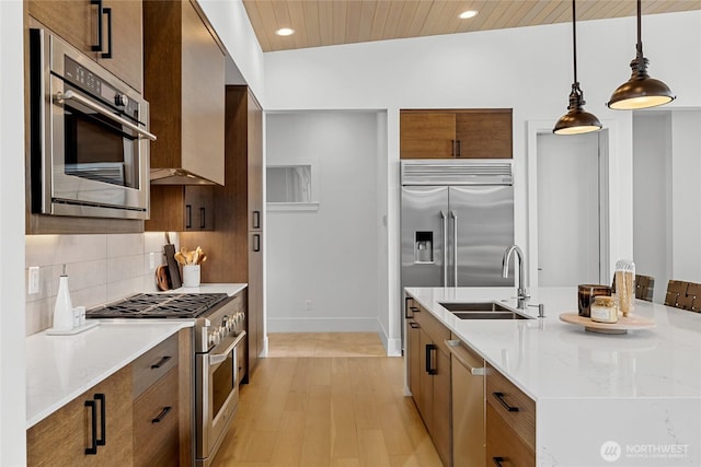 kitchen with a sink, pendant lighting, high quality appliances, modern cabinets, and backsplash