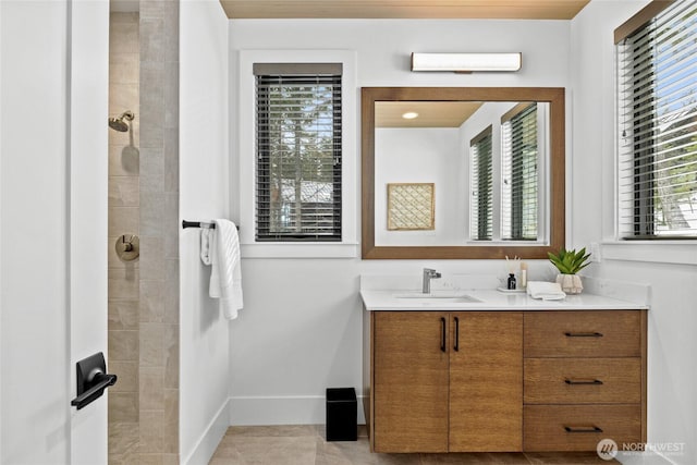 bathroom featuring baseboards, vanity, and a tile shower