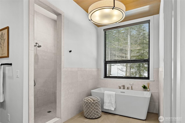 bathroom featuring a freestanding tub, tile walls, a tile shower, and tile patterned flooring