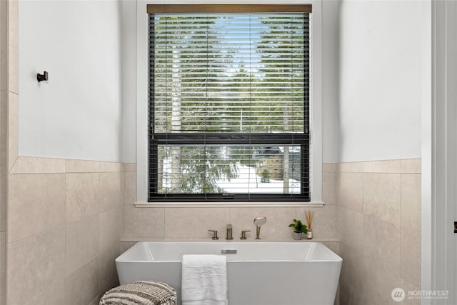 bathroom featuring a soaking tub and tile walls