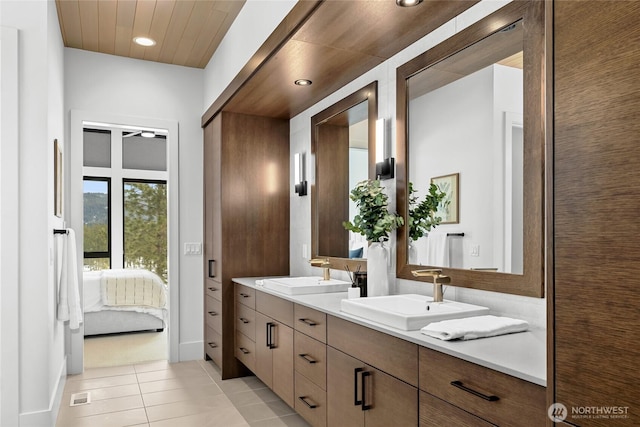 bathroom with a sink, double vanity, ensuite bathroom, and tile patterned floors