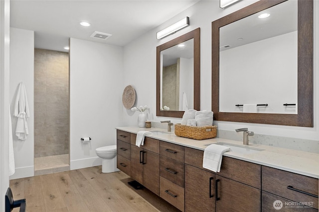 full bathroom with a sink, visible vents, toilet, and wood finished floors