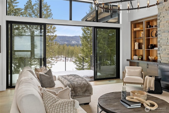 interior space with built in features, wood finished floors, a towering ceiling, and a chandelier