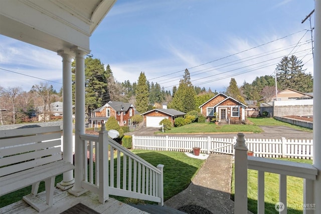 view of yard with a garage, a porch, a fenced front yard, and a residential view