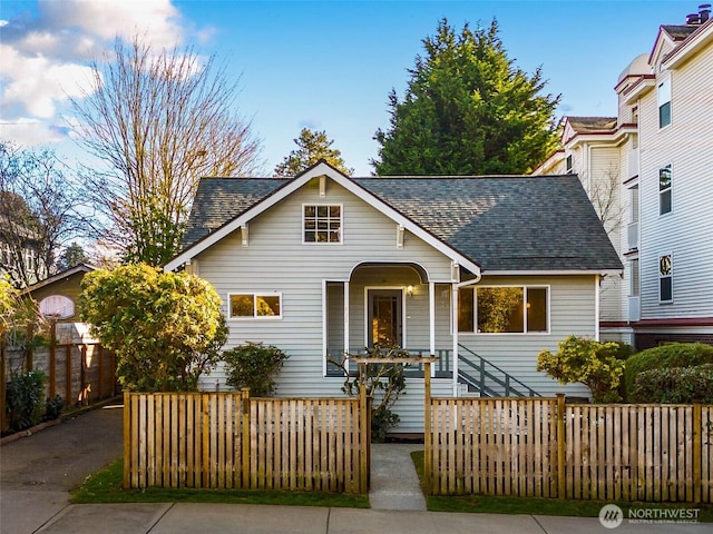 view of front of home with roof with shingles and fence