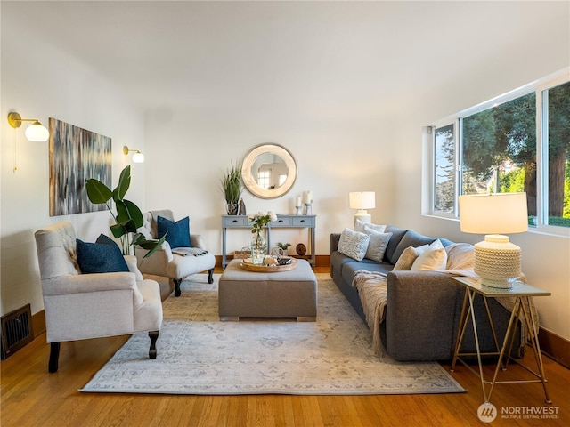 living room featuring visible vents, baseboards, and wood finished floors