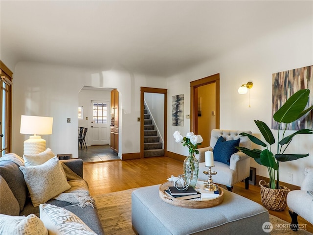 living room featuring stairway, wood finished floors, visible vents, baseboards, and arched walkways