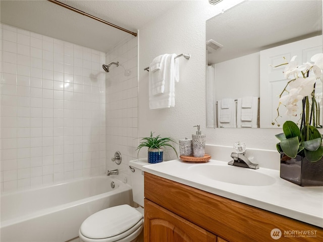 bathroom with visible vents, toilet, a textured wall, vanity, and  shower combination