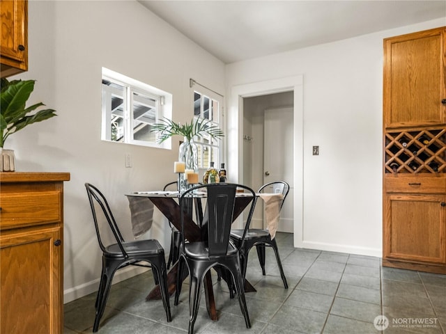 tiled dining room featuring baseboards