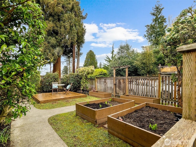 view of yard with fence, a deck, and a garden