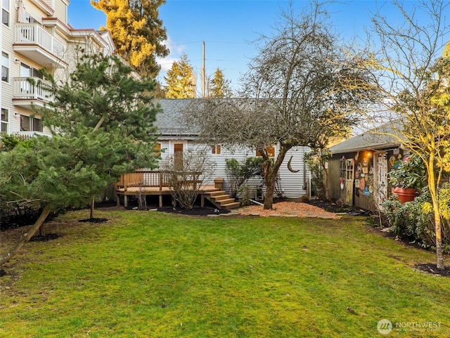 rear view of house with a deck, a lawn, and a shingled roof