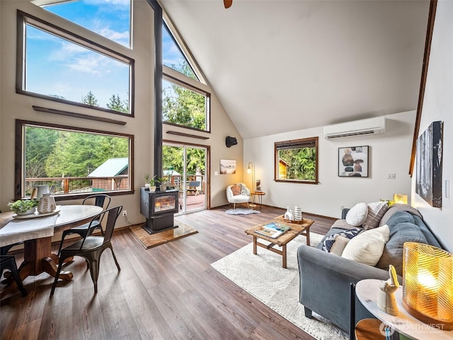 living area featuring baseboards, a wall mounted air conditioner, a wood stove, wood finished floors, and high vaulted ceiling