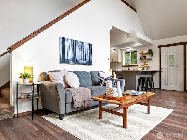 living room with stairs, baseboards, dark wood-type flooring, and high vaulted ceiling