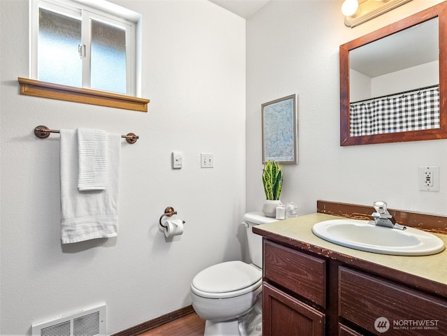 bathroom with visible vents, toilet, vanity, and wood finished floors