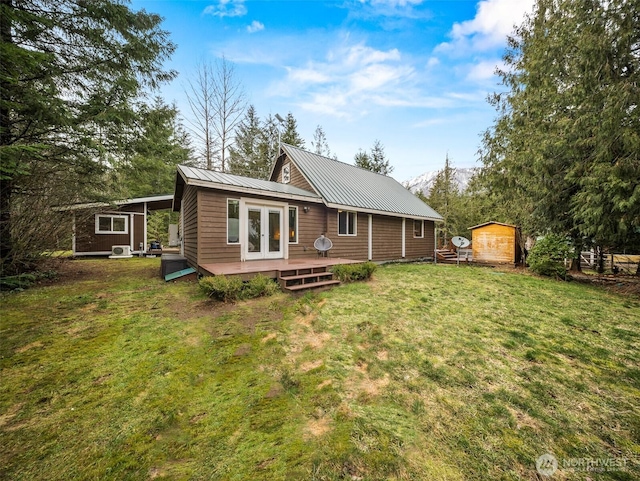 rear view of house featuring an outbuilding, a deck, french doors, a yard, and metal roof