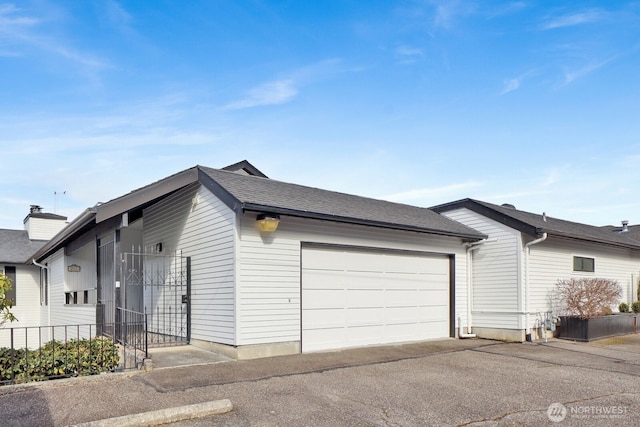 view of home's exterior with an attached garage and a shingled roof