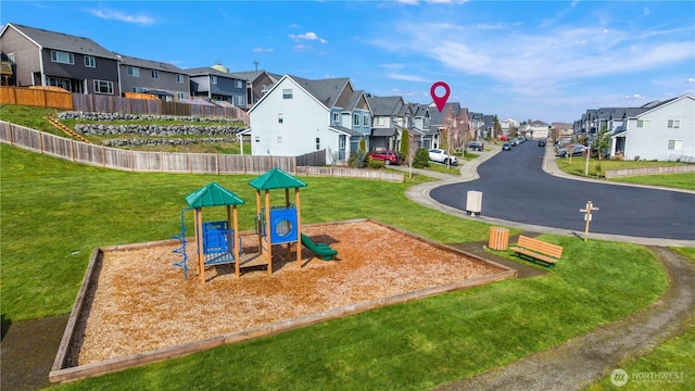 community jungle gym featuring a yard, a residential view, and fence